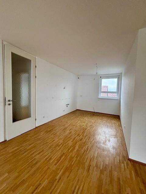 Helles Zimmer mit Parkettboden und einer Tür mit Milchglas, die für Privatsphäre sorgt.