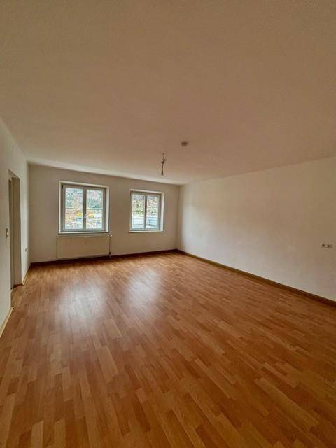 Heller Wohnbereich mit zwei Fenstern, Laminatboden und viel Potenzial zur individuellen Gestaltung.