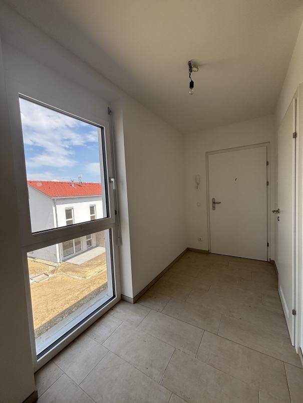 Heller Eingangsbereich mit Fliesenboden und großem Fenster, bietet einen freundlichen Empfang.