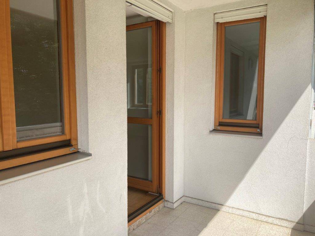 Balkonbereich mit Holztür und Fenster, ausgestattet mit Außenrollläden für Privatsphäre.