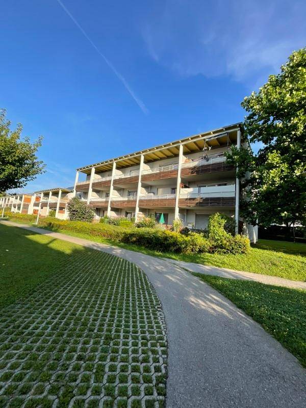 Ansicht eines modernen Mehrfamilienhauses mit Balkonen und grüner Umgebung an einem sonnigen Tag.