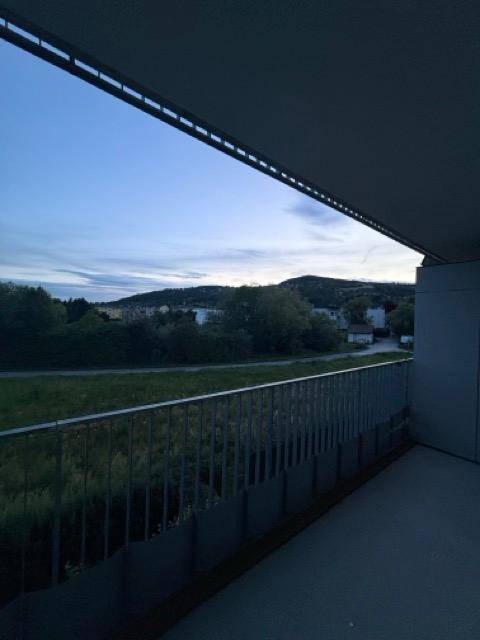 Balkon mit weitem Blick über grüne Felder und die umliegende Landschaft am Abend.