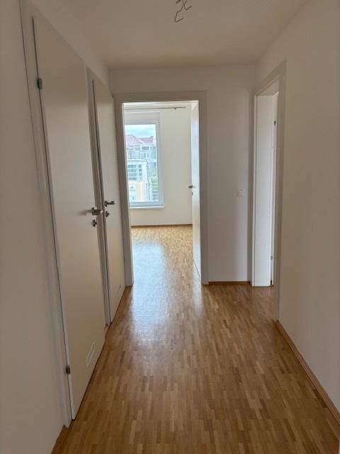 Heller Flur mit Parkettboden, der den Zugang zu verschiedenen Zimmern der Wohnung ermöglicht.