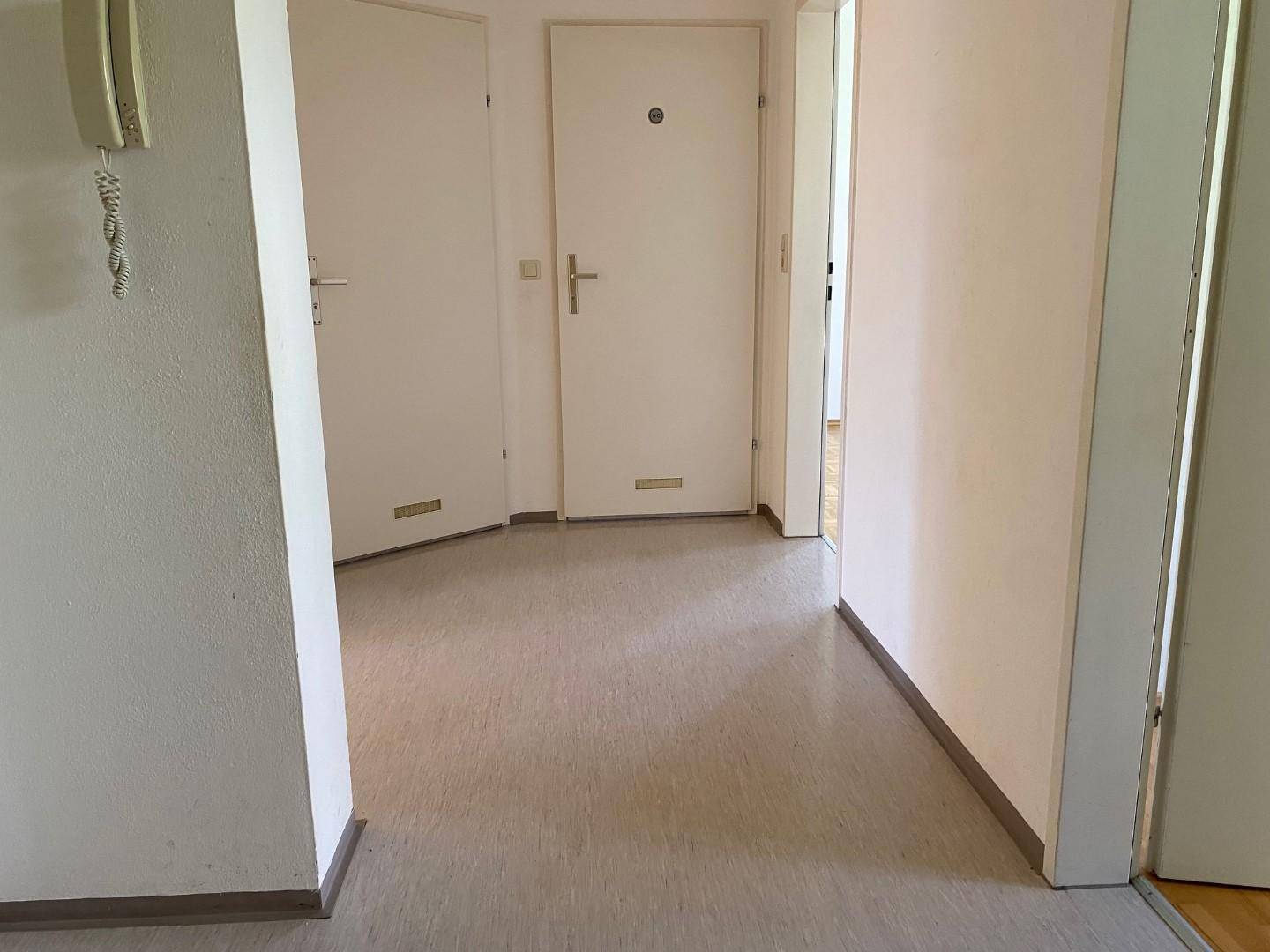 Heller Flur mit strapazierfähigem Bodenbelag und mehreren Türen zu den angrenzenden Räumen.