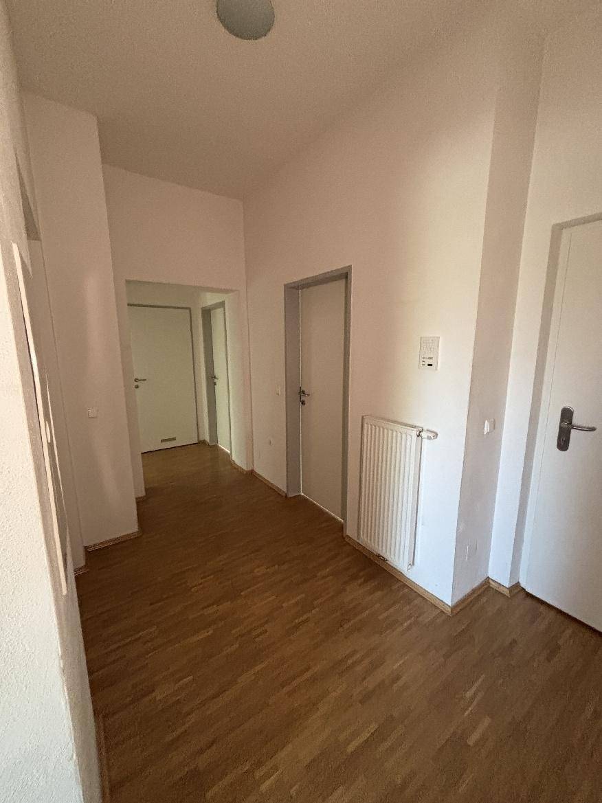 Heller Flur mit Parkettboden und mehreren Türen, der zu verschiedenen Räumen führt.