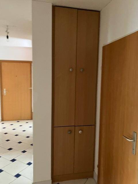 Heller Flur mit Einbauschrank und Fliesenboden in Schachbrettmuster.