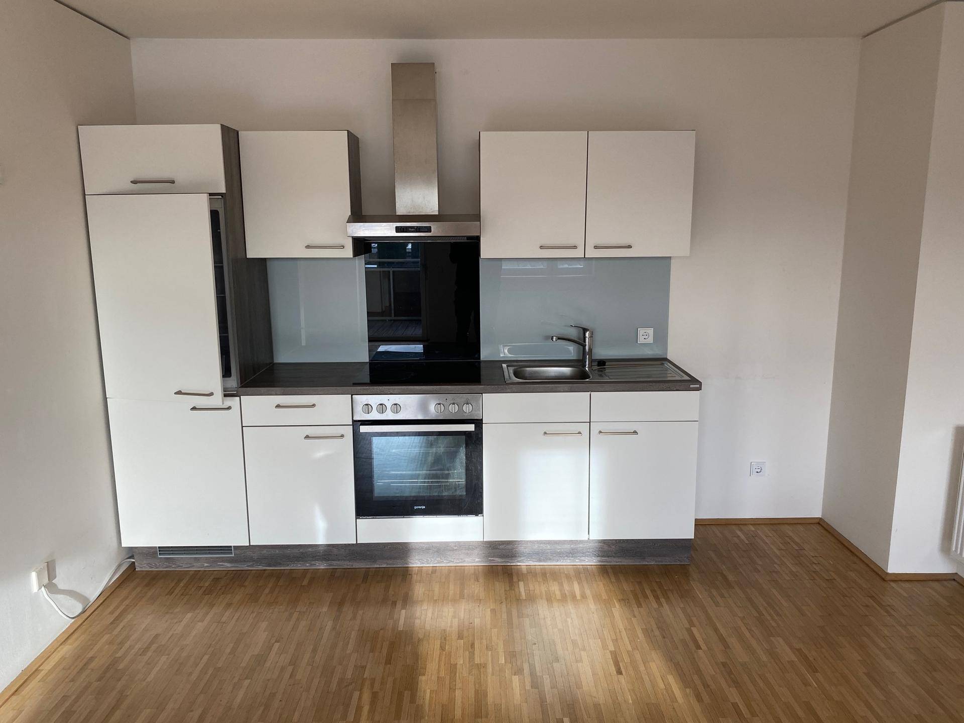 Moderne Einbauküche mit weißen Schränken, Backofen und Dunstabzugshaube.