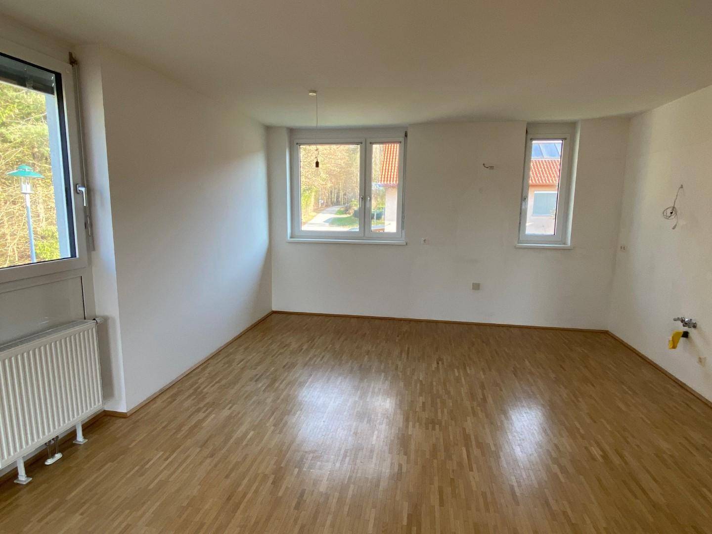 Geräumiges Zimmer mit Parkettboden und mehreren Fenstern, die viel Tageslicht hereinlassen.
