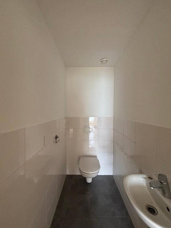 Kleines Gäste-WC mit Wand-WC, Waschbecken und dunklen Bodenfliesen, praktisch und funktional.