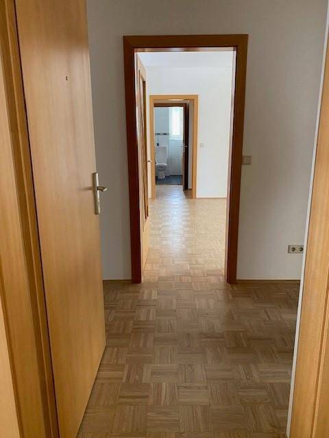 Heller Flur mit Parkettboden und Holztüren, der den Blick in weitere Zimmer freigibt.