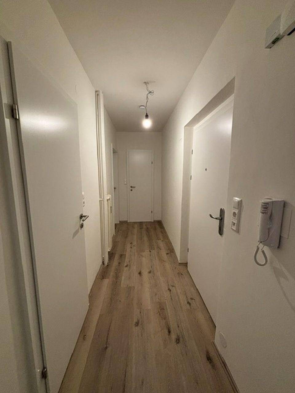 Heller Flur mit Laminatboden und mehreren weißen Türen, der zu weiteren Räumen in der Wohnung führt.