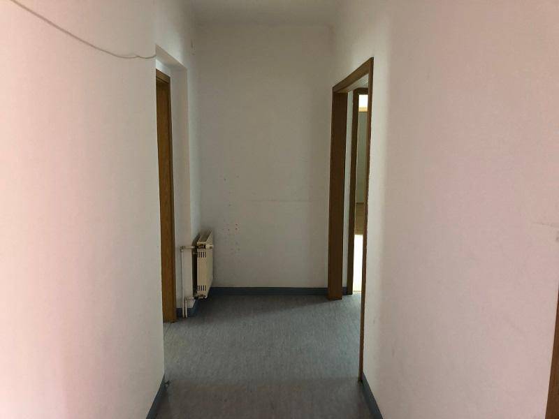 Leerer Flur mit Heizkörper und Türen zu angrenzenden Zimmern.