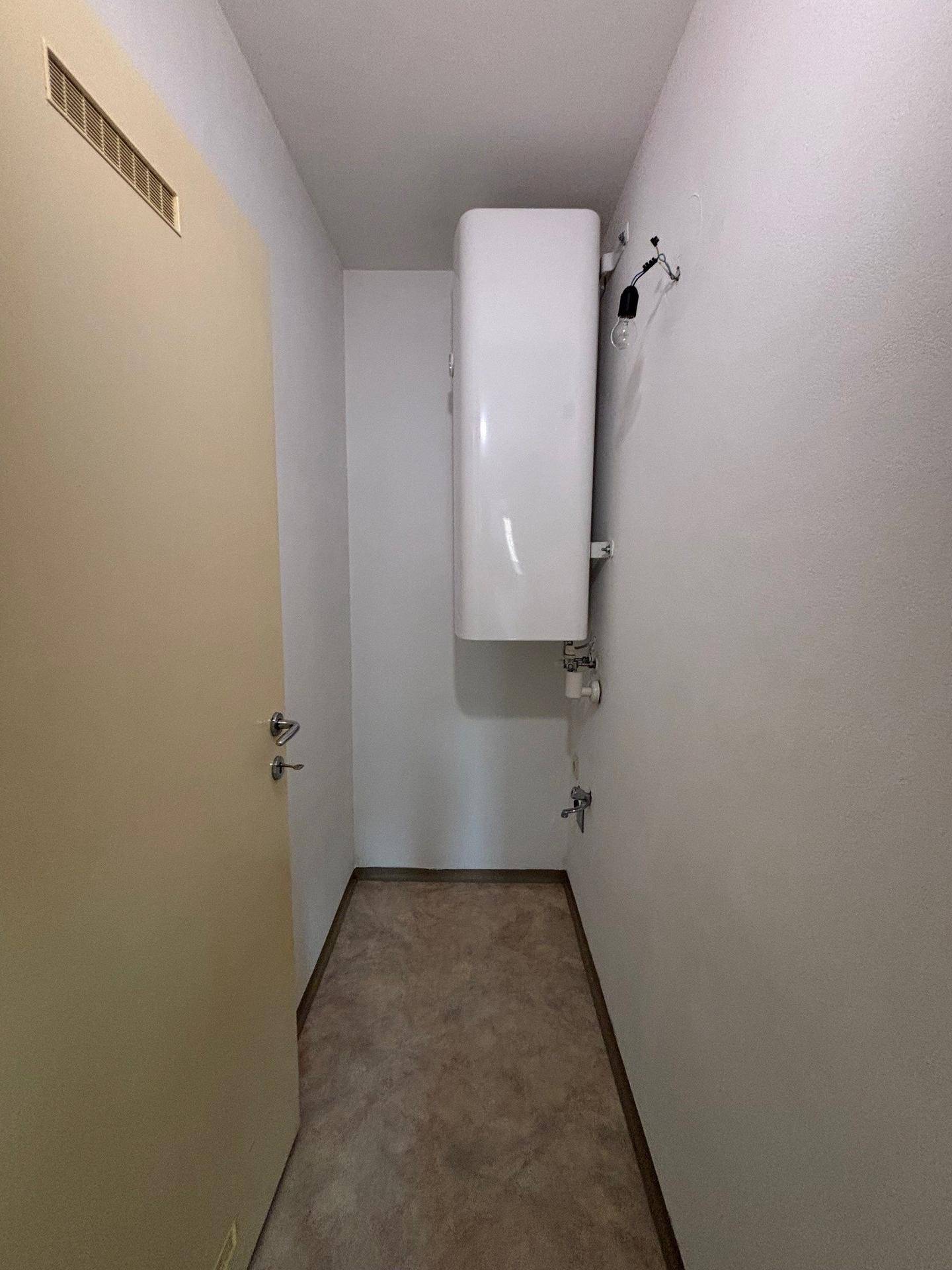 Kleiner Abstellraum mit Warmwasserboiler und praktischem Bodenbelag für den täglichen Gebrauch.