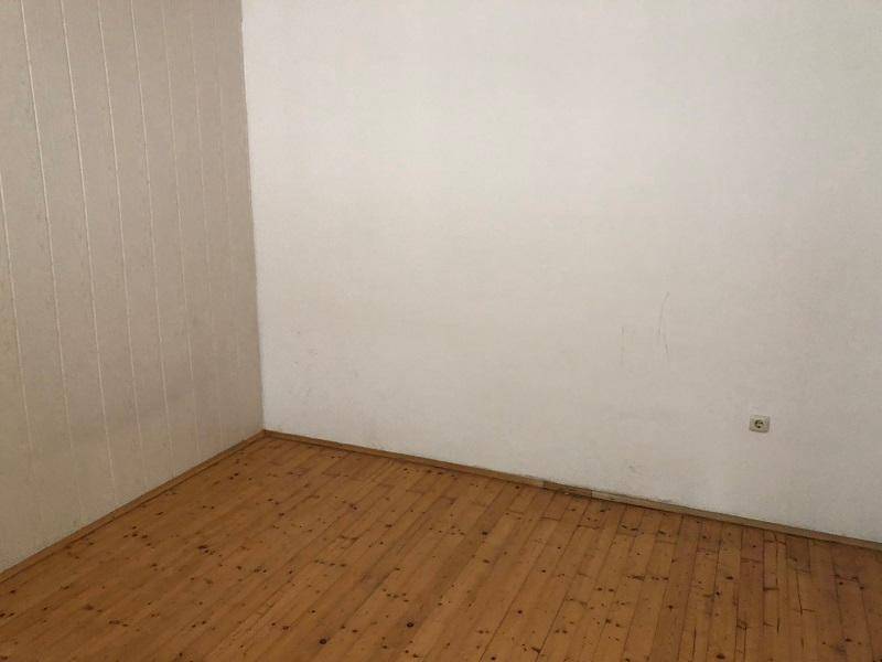 Leeres Zimmer mit hellen Wänden und warmem Holzdielenboden.