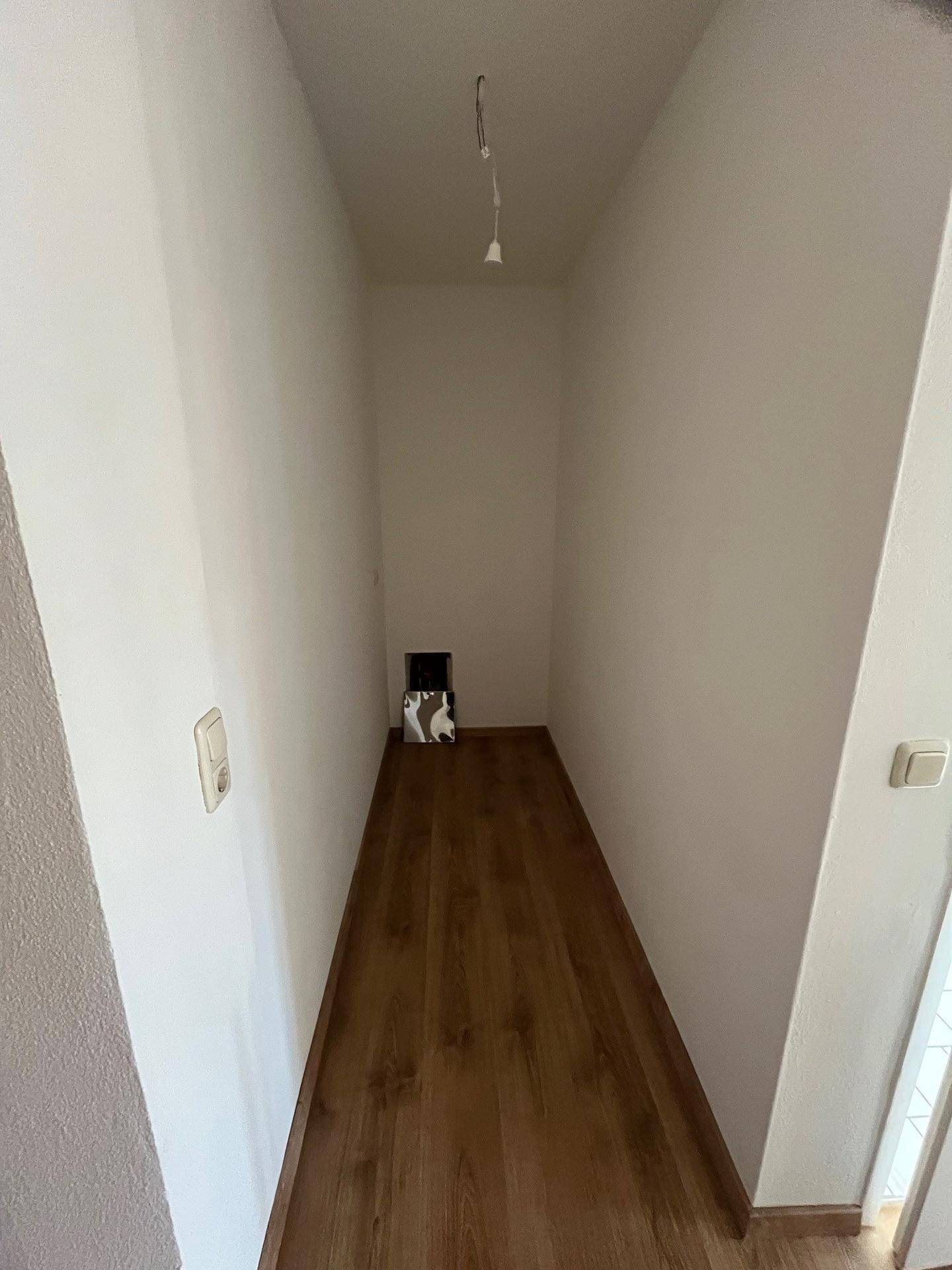 Schmaler Abstellraum mit Laminatboden und Anschlussmöglichkeiten, ideal für Haushaltsgeräte oder Lagerung.
