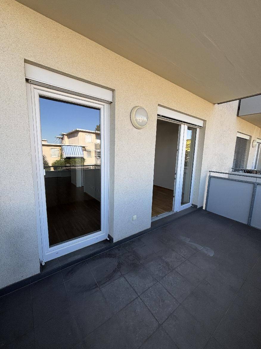Geräumiger Balkon mit Fliesenboden und Blick auf die Umgebung, ideal zum Entspannen.
