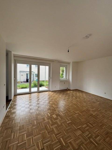 Geräumiges Wohnzimmer mit Parkettboden und großen Schiebetüren zum Garten.