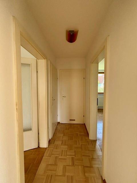 Heller Flur mit Parkettboden und mehreren Türen, die zu den angrenzenden Räumen führen.