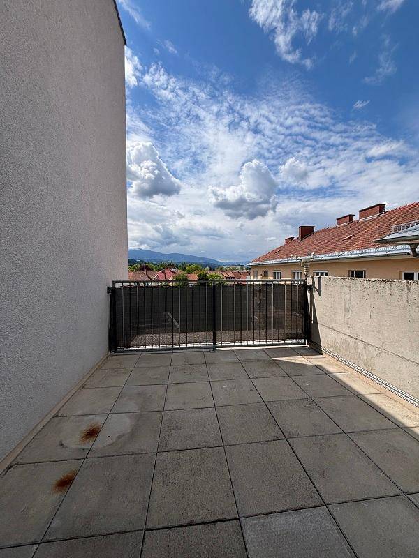 Offener Balkon mit Fliesenboden und weitem Blick auf die Stadt und die Berglandschaft.