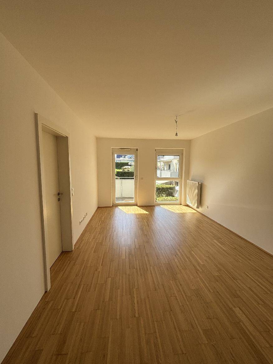 Helles Wohnzimmer mit Holzboden und Zugang zu einem Balkon.
