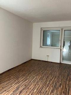 Heller Raum mit Laminatboden und großem Fenster, das viel Tageslicht hereinlässt.