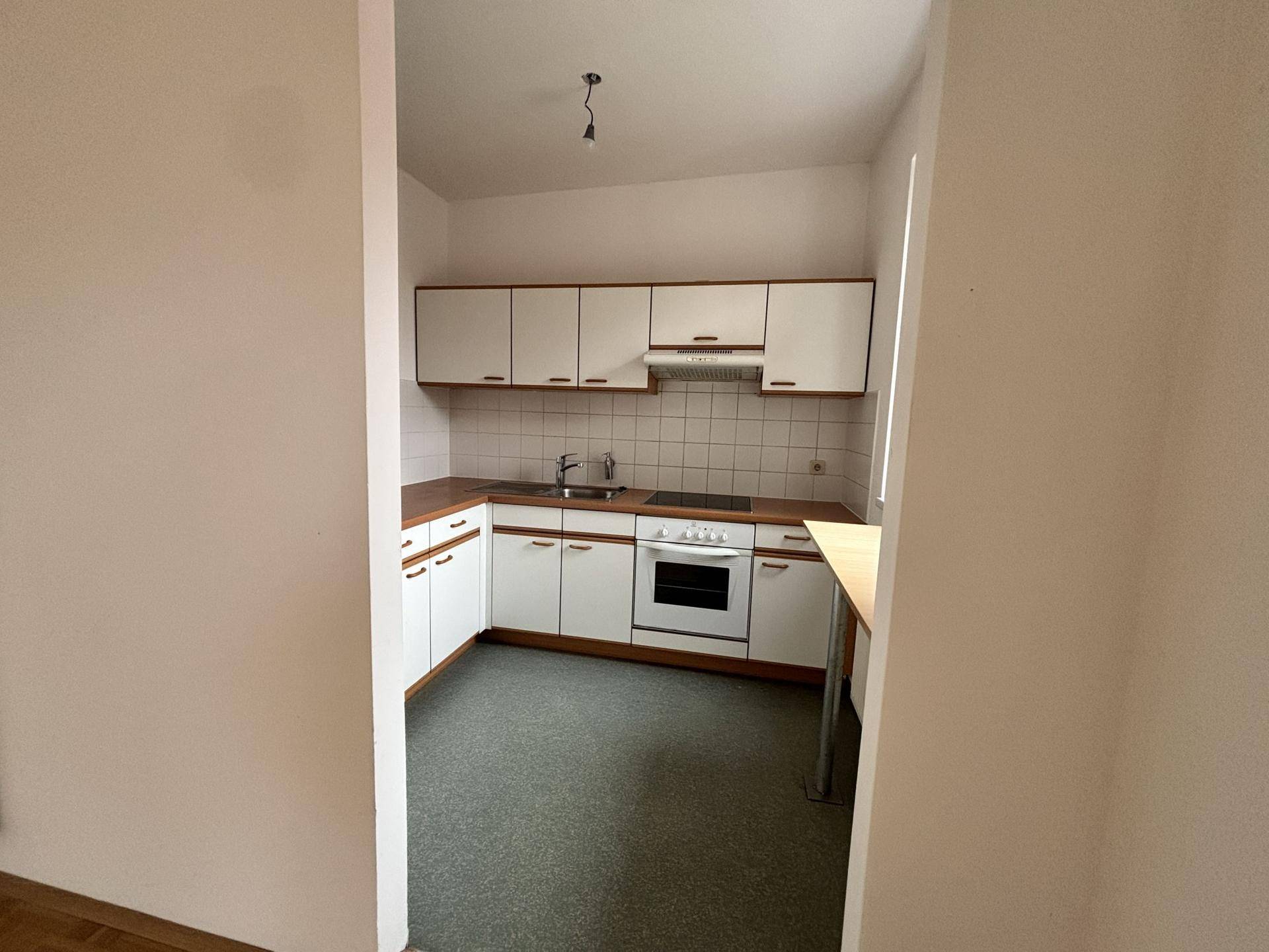 Funktionale Küche mit weißen Schränken, Holzarbeitsplatte und integrierten Geräten.