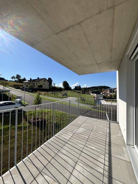 Geräumiger Balkon mit Fliesenboden und Metallgeländer, bietet einen weiten Blick auf die Umgebung.