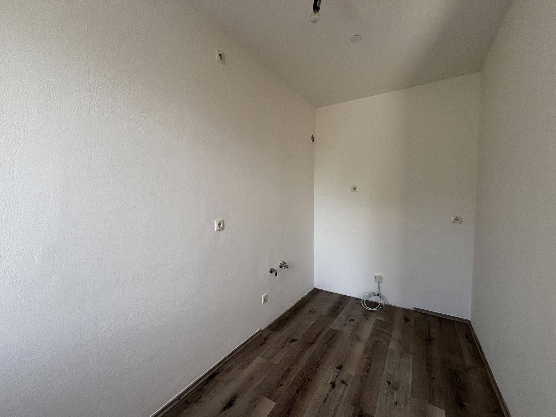 Leere Küche mit Anschlüssen für Spüle und Geräte, bereit für die individuelle Gestaltung.
