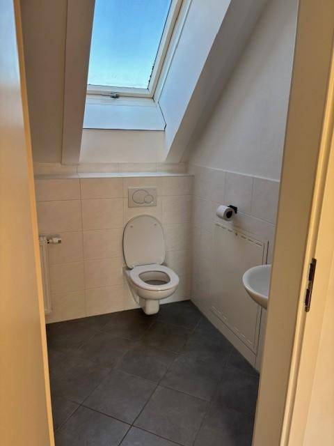 Kleines Gäste-WC im Dachgeschoss mit Toilette, Fliesenboden und Dachfenster.