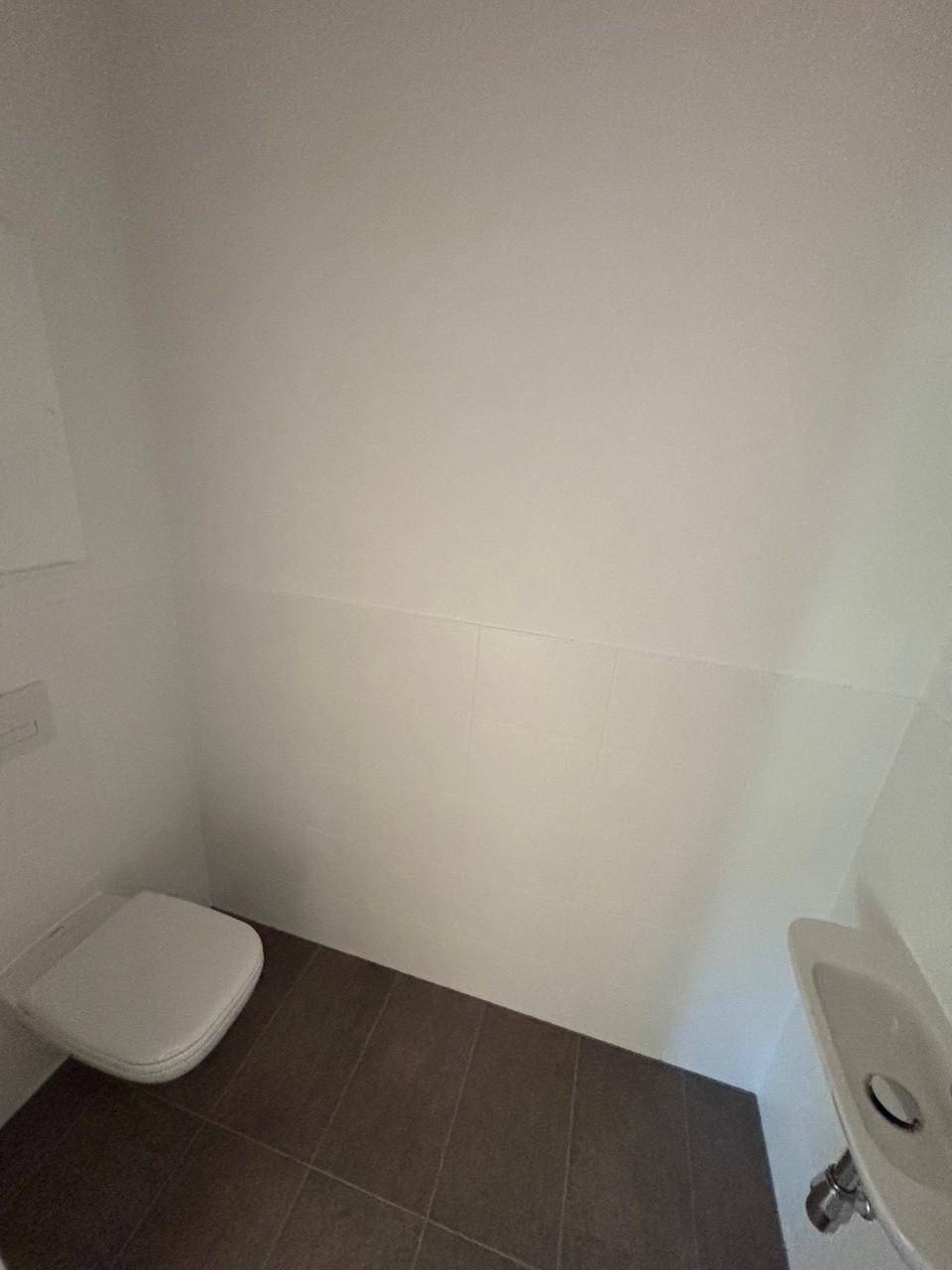 Kleines Gäste-WC mit wandhängender Toilette und einem kompakten Waschbecken.