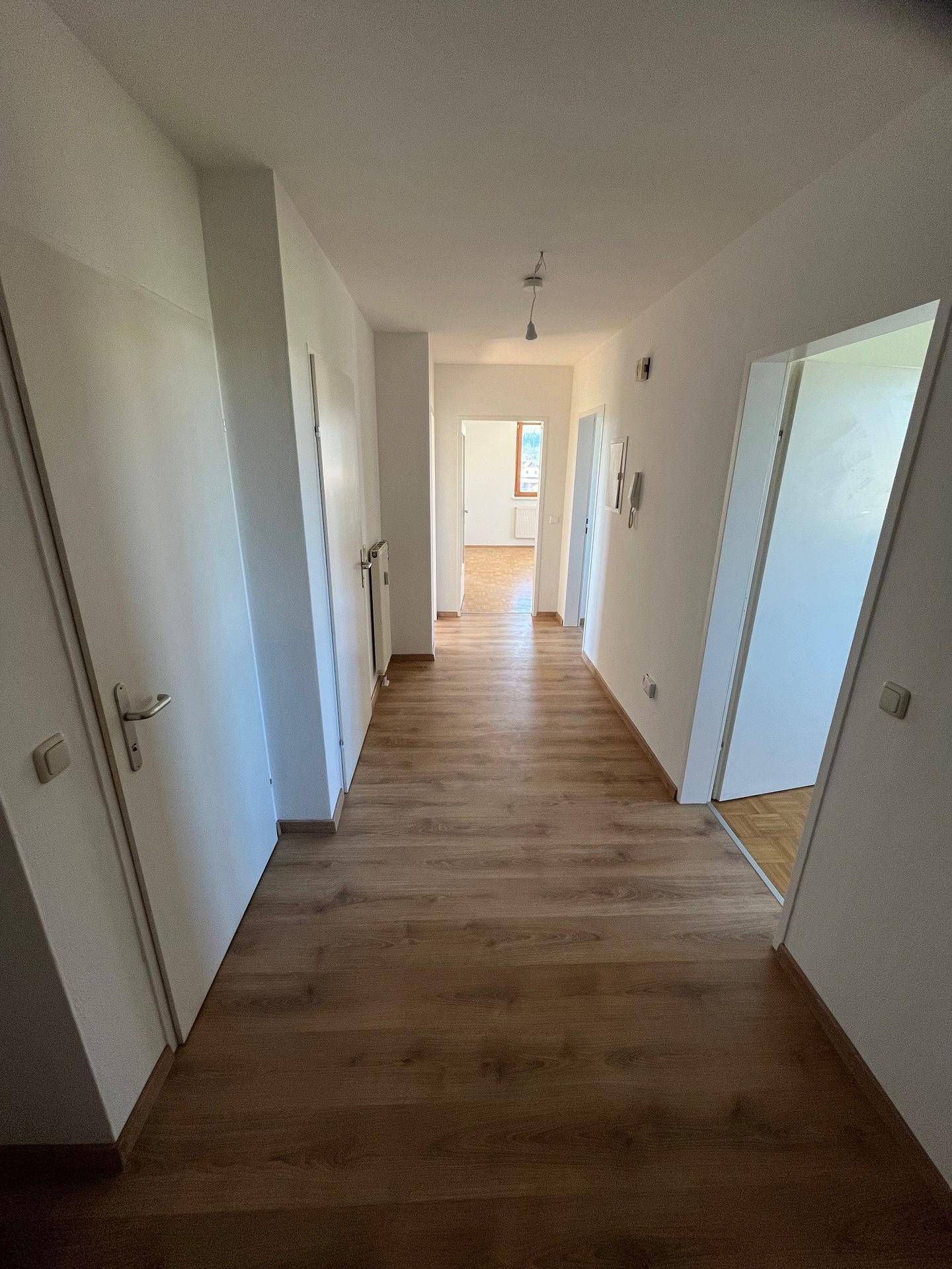 Langer, heller Flur mit Laminatboden und Zugang zu verschiedenen Räumen im Inneren der Wohnung.