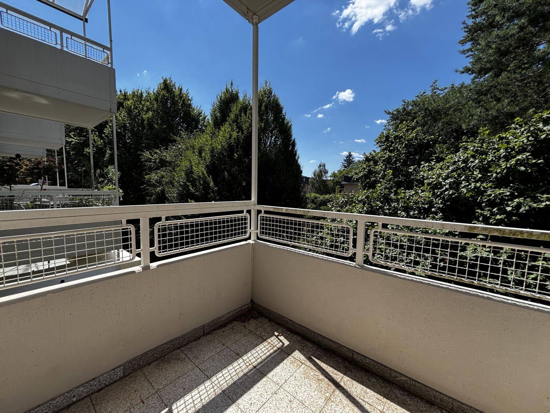 Geräumiger Balkon mit Fliesenboden und weitem Blick auf die umliegende grüne Landschaft.