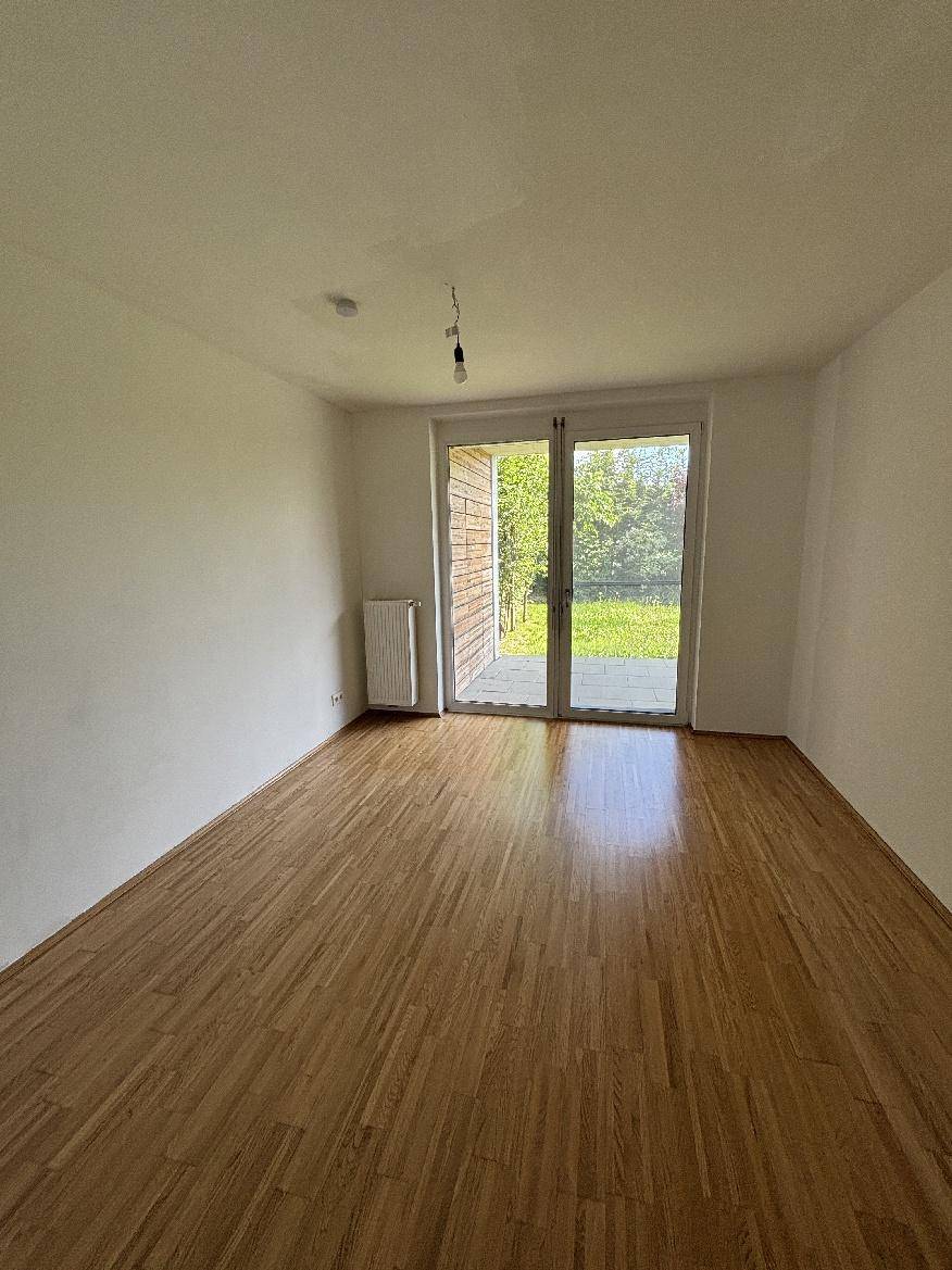 Lichtdurchflutetes Schlafzimmer mit Holzparkett und Zugang zu einer Terrasse oder dem Garten.