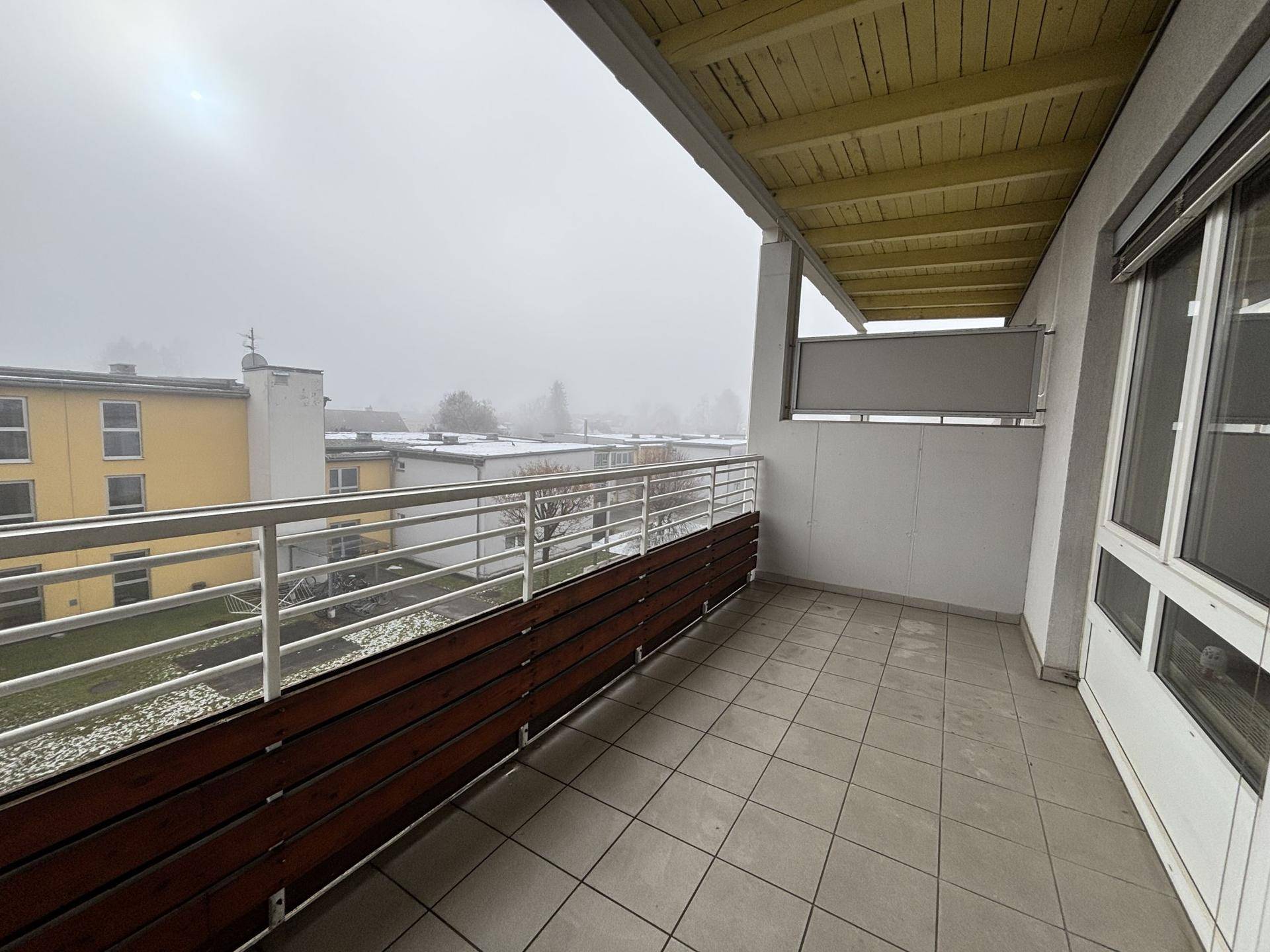 Geräumiger Balkon mit Fliesenboden und Blick auf die umliegenden Gebäude.