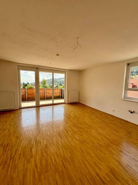 Geräumiges Wohnzimmer mit Parkettboden und Zugang zu einem Balkon mit Bergblick.