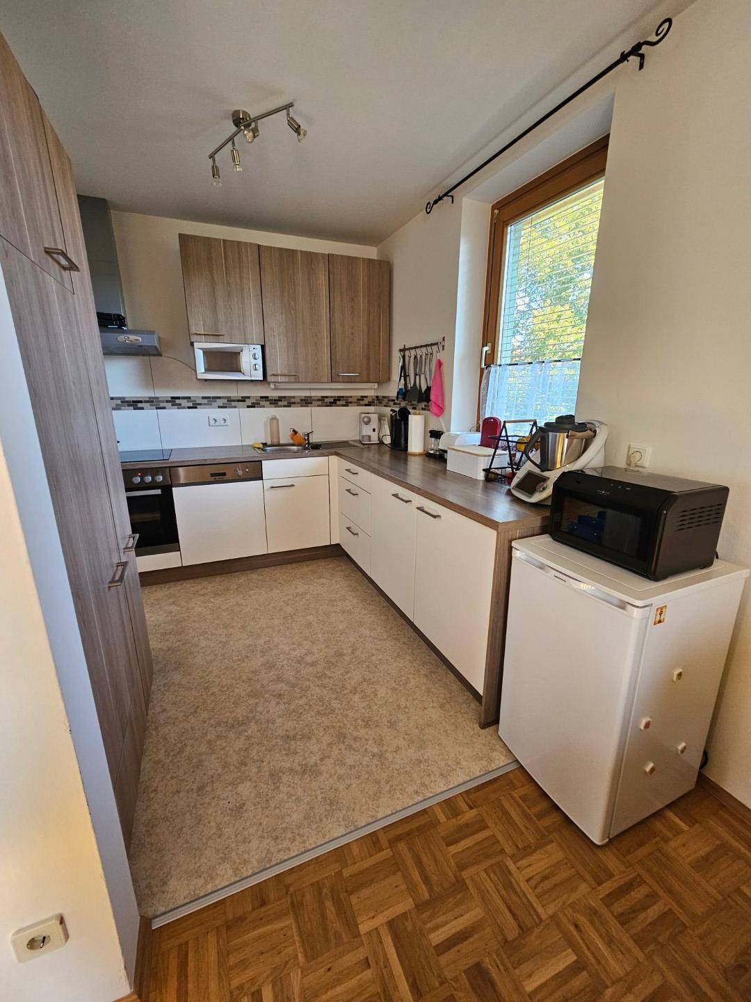 Funktionale Küche mit Holz- und weißen Schränken, Herd und Mikrowelle.