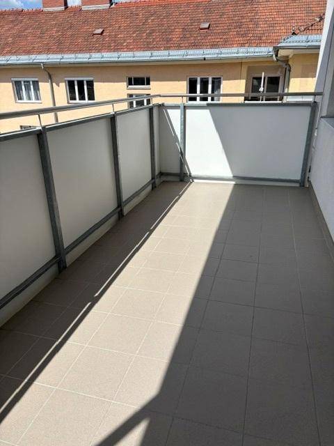 Langer Balkon mit Fliesenboden und Metallgeländer, ideal für Entspannung im Freien.