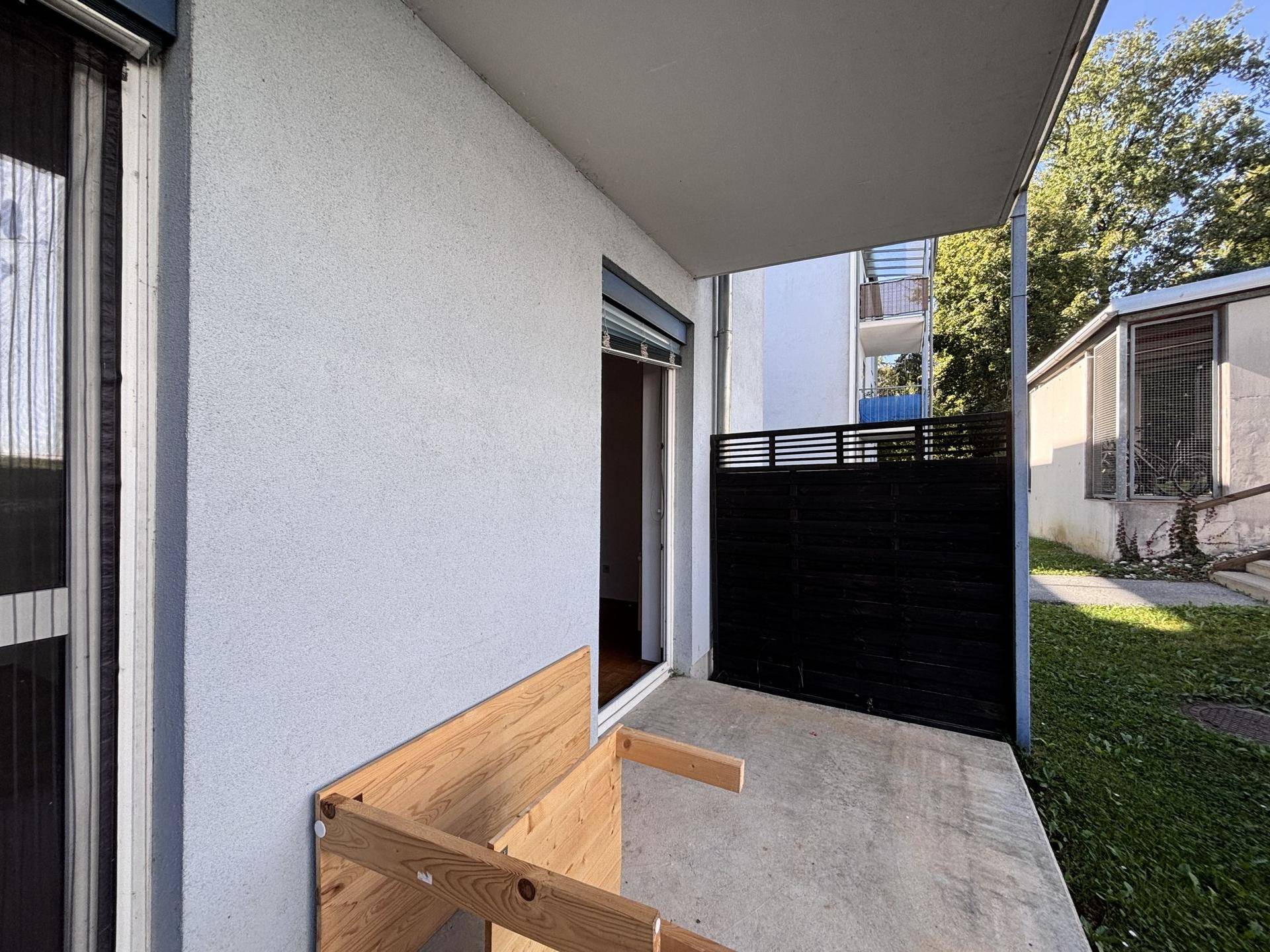 Überdachte Terrasse mit Zugang zum Garten und einer Holztrennwand.