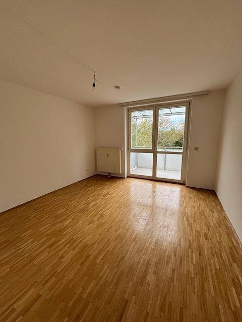Helles Zimmer mit Parkettboden und direktem Zugang zum überdachten Balkon.