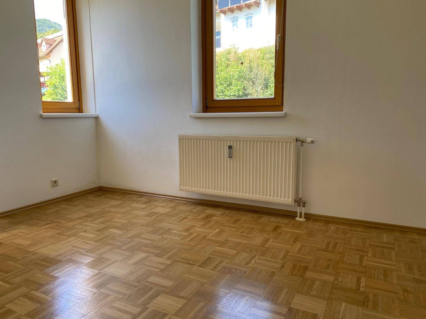 Helles Schlafzimmer mit zwei Fenstern, Parkettboden und angenehmer Atmosphäre.