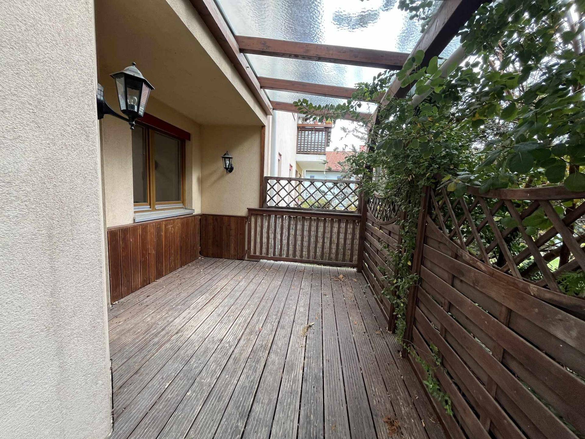 Geräumige überdachte Holzterrasse mit Holzzaun und viel Platz für Gartenmöbel.