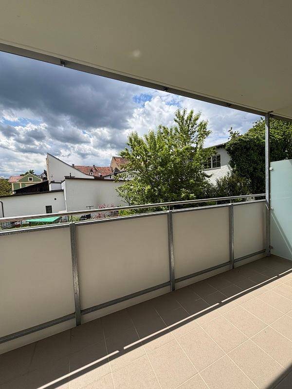 Heller Balkon mit Fliesenboden und einer schönen Aussicht auf die grüne Umgebung.