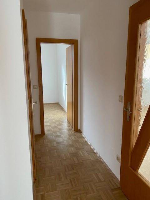 Heller Flur mit Parkettboden und Holztüren, der den Zugang zu verschiedenen Räumen ermöglicht.