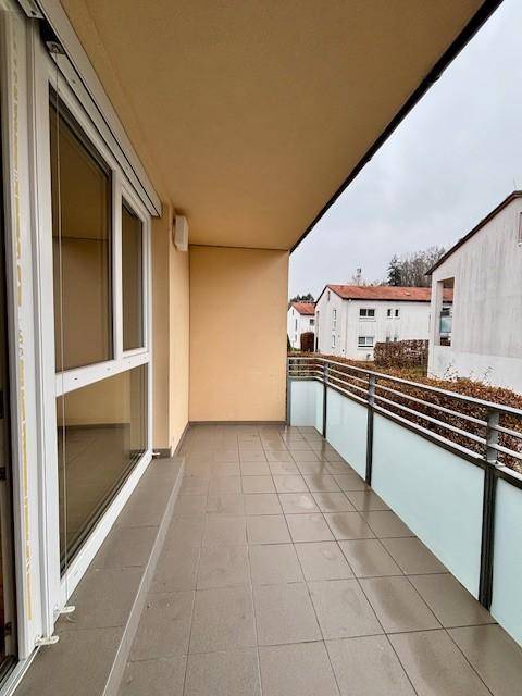 Geräumiger Balkon mit Fliesenboden und Glasgeländer, bietet einen Blick auf die Umgebung.
