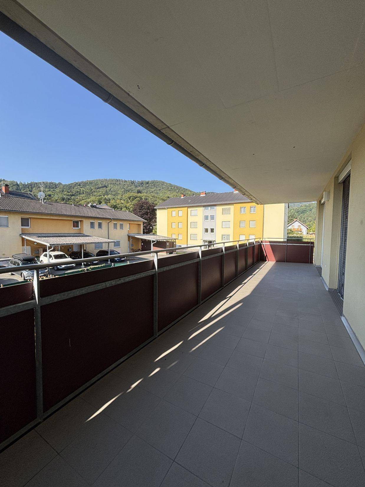 Geräumiger Balkon mit weitem Blick über die Dächer der Nachbarschaft und die umliegende Landschaft.