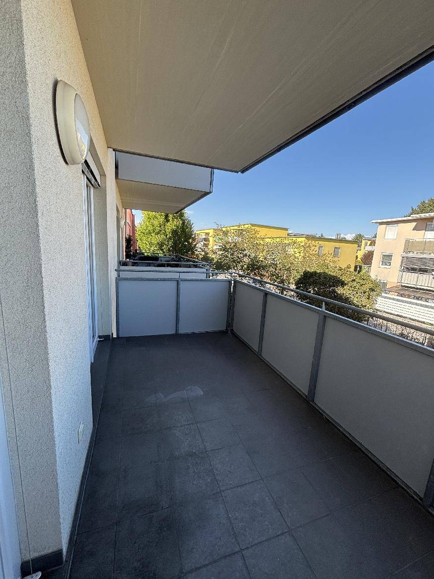 Sonniger Balkon mit Markise und weitem Blick über die umliegende Wohngegend.
