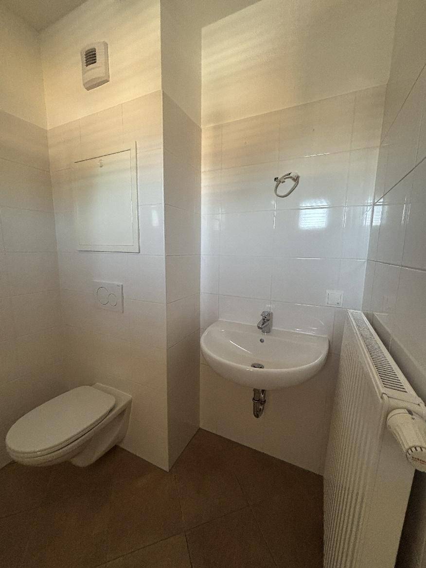 Modernes Badezimmer mit wandhängendem WC, Waschbecken und weißen Fliesen.