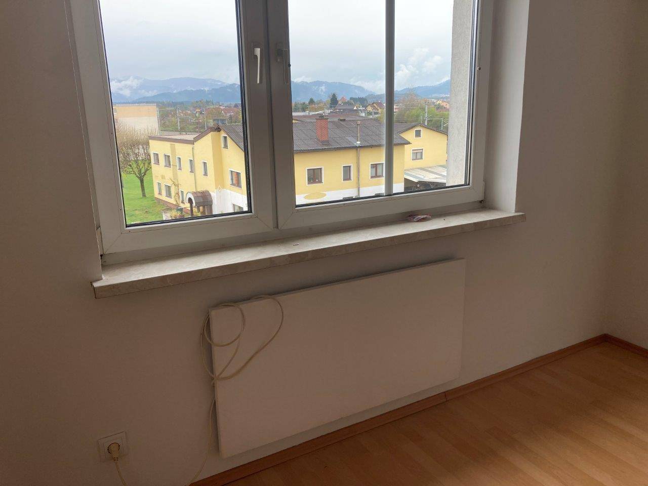 Fensterbereich mit Heizkörper und Blick auf die umliegenden Gebäude und die Berglandschaft.