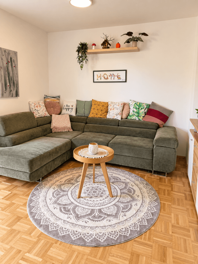 Gemütliches Wohnzimmer mit Ecksofa, Parkettboden und farbenfrohen Kissen.