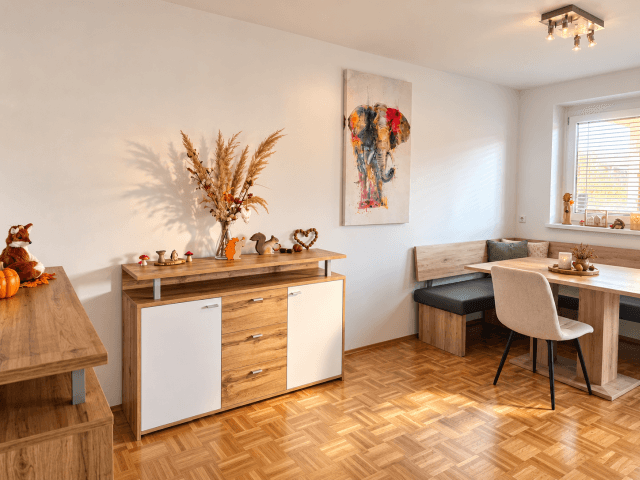 Heller Essbereich mit Holztisch, Eckbank und modernem Sideboard, dekoriert für den Herbst.